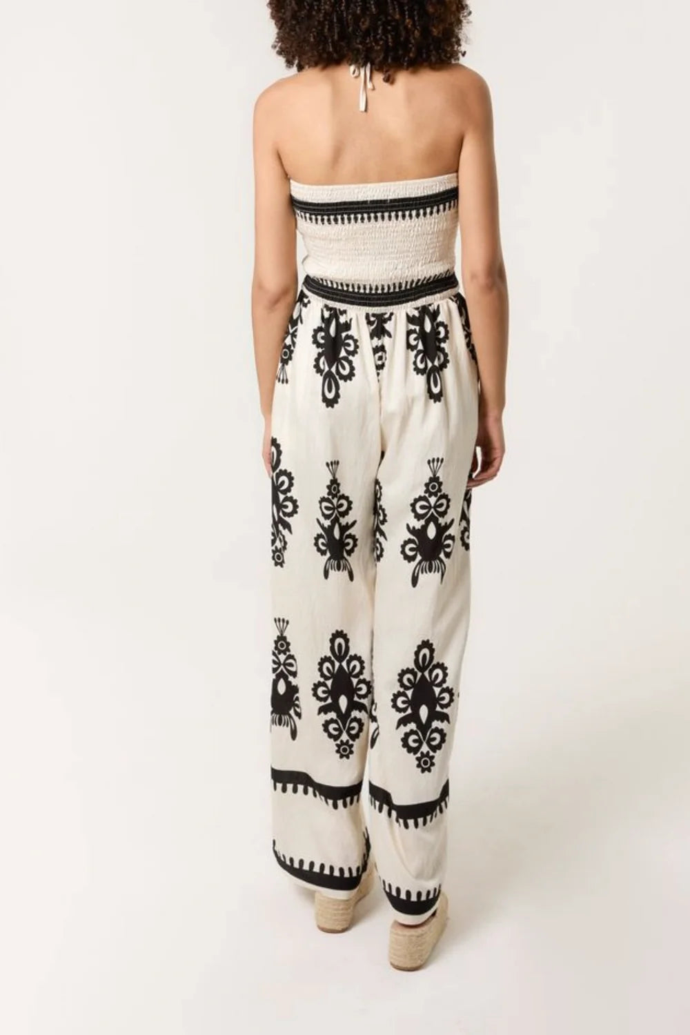 Elegant halterneck jumpsuit in stone with a shirred bodice and vibrant print, crafted from a soft viscose blend.