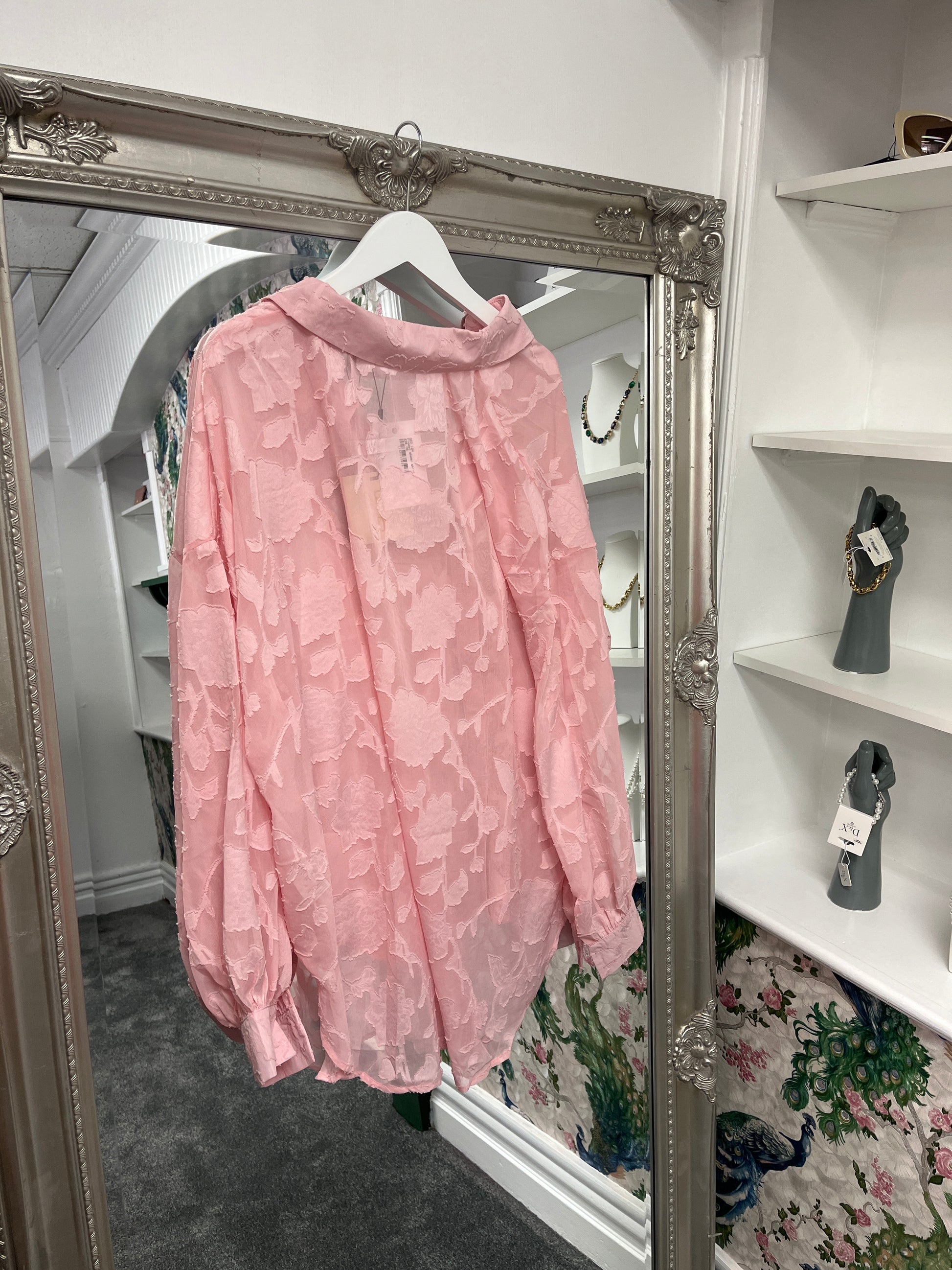 Delicate pink sheer shirt with a floral pattern, crafted from 100% polyester, styled on a model for a breezy, elegant look.
