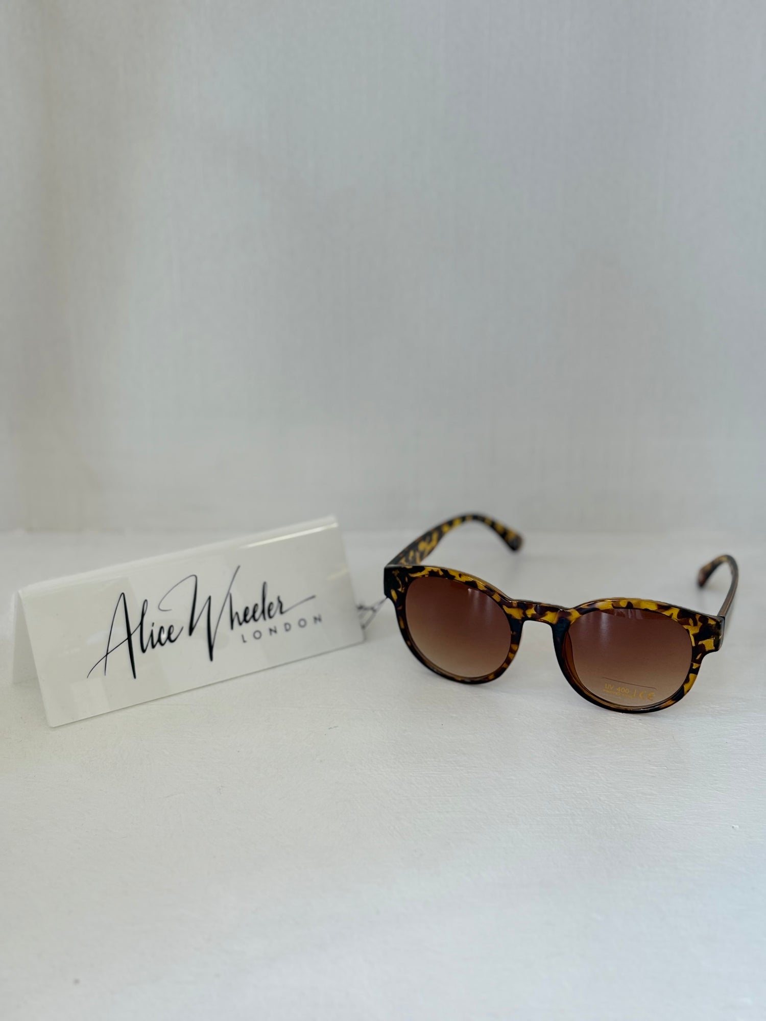 Round Alice Wheeler Sunglasses in tortoise colour on white background with Alice Wheeler sign