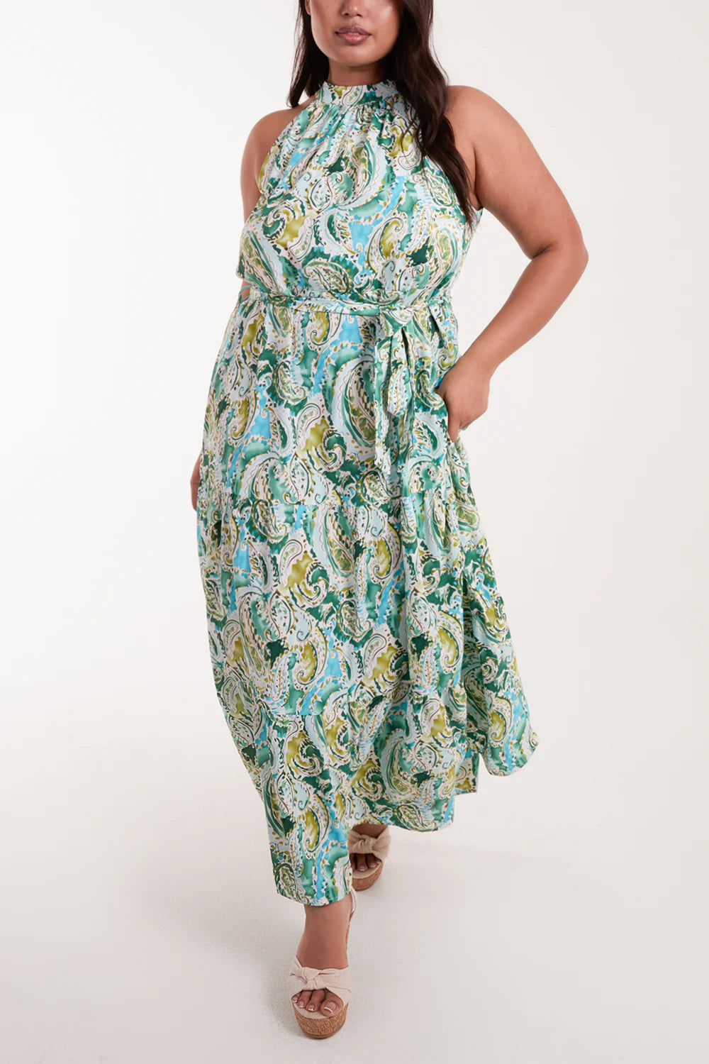 Vibrant green paisley maxi dress with a halter neckline, belted waist, and flowing tiered skirt for a stunning summer look.