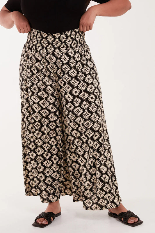 Vibrant plus-size geometric trousers with a wide shirred waistband, showcasing a colorful boho pattern for stylish summer wear.